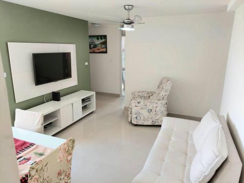 a living room with a television and a chair at Ótimo apartamento, bem localizado in Aracaju