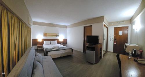 a hotel room with a bed and a television at Flat Borges Lagoa Vl Mariana Ibirapuera com garagem UH1007 in Sao Paulo