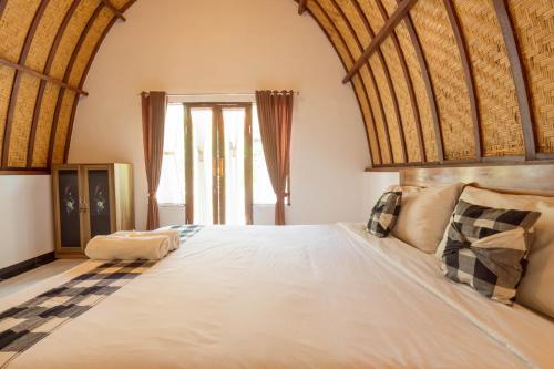a bedroom with a large bed with a wooden ceiling at Ratu Cottage by OurStory Travels in Nusa Penida