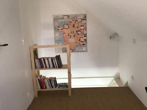 une étagère avec des livres et une carte sur le mur dans l'établissement Petite dépendance comme la cabine d’un bateau., à Saint-Armel