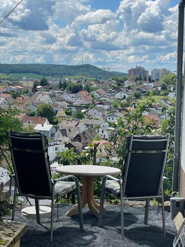 2 Stühle und ein Tisch auf einem Balkon mit einer Stadt in der Unterkunft Ferienwohnung Panoramablick in Sinsheim