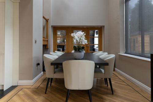 a dining room with a black table and white chairs at The Luxury House in Swanland