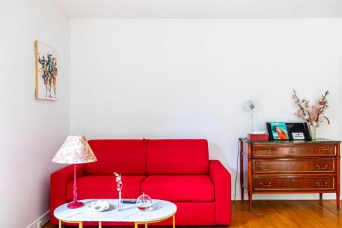 un soggiorno con un divano rosso e un tavolo di GuestReady - Stylish haven near La Seine Musicale a Meudon