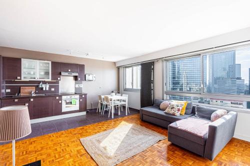 a living room with a couch and a kitchen at GuestReady - Modern chic with a view in La Défense