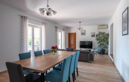 a dining room and living room with a wooden table and blue chairs at Lovely Home In Loborika in Loborika