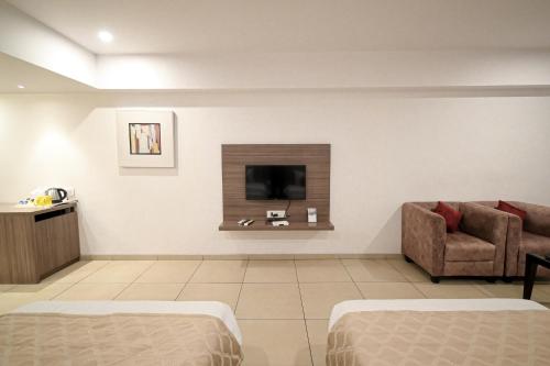 uma sala de estar com um sofá e uma televisão na parede em Hotel Dwarkamai em Nagpur