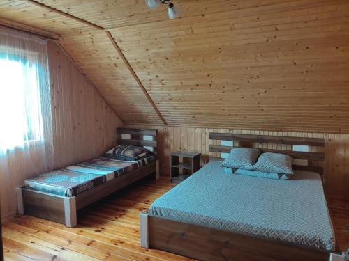 a bedroom with two beds in a wooden cabin at Сімейний куточок in Svityazʼ