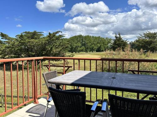 a table and chairs on a deck with a view of a field at 110 - Appartement duplex 6 personnes vue sur Golf. in Frehel