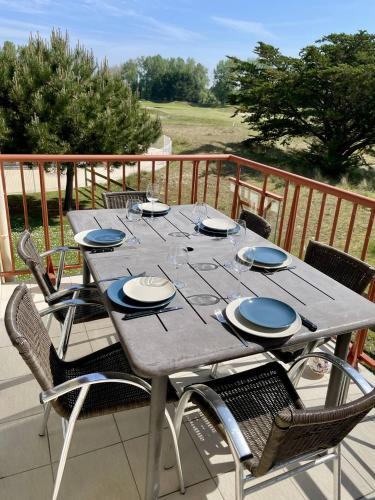 a gray table with chairs and plates on a deck at 110 - Appartement duplex 6 personnes vue sur Golf. in Frehel