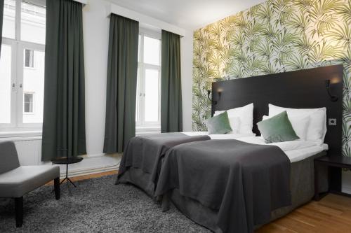 um quarto com uma cama, uma cadeira e janelas em Clarion Collection Hotel Plaza em Karlstad