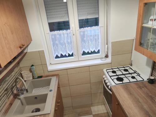 kuchnia ze zlewem i kuchenką oraz 2 okna w obiekcie Tavasz apartman w mieście Balatonfenyves