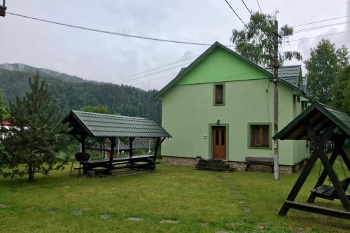 a green house with a picnic table in front of it at Goryanka family home in Mykulychyn