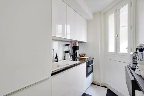 une cuisine blanche avec un évier et une fenêtre dans l'établissement Appartement au centre de Paris tout équipé, à Paris