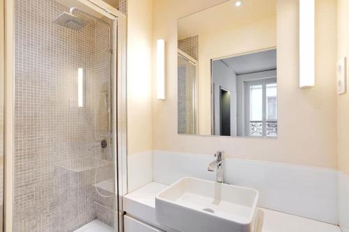 une salle de bain blanche avec un lavabo et une douche dans l'établissement Appartement au centre de Paris tout équipé, à Paris