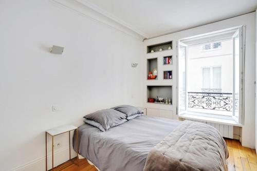 une chambre blanche avec un lit et une fenêtre dans l'établissement Appartement au centre de Paris tout équipé, à Paris