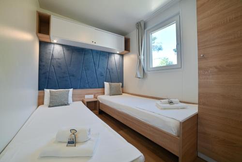 twee bedden in een kleine kamer met een raam bij Kamp Rožac in Trogir
