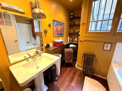 une salle de bain avec un lavabo et un miroir dans l'établissement Le Penthouse Guy Moquet, à Paris
