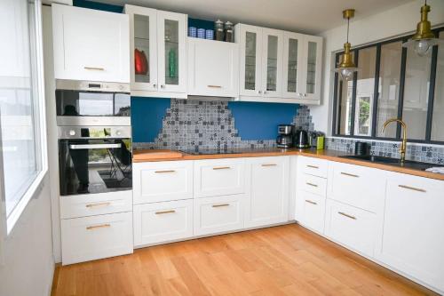 Il comprend une cuisine blanche avec des placards blancs et du parquet. dans l'établissement le lenn La Maison Du Lenn Exceptional location, à Louannec