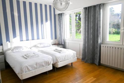 deux lits dans une chambre avec deux fenêtres dans l'établissement le lenn La Maison Du Lenn Exceptional location, à Louannec