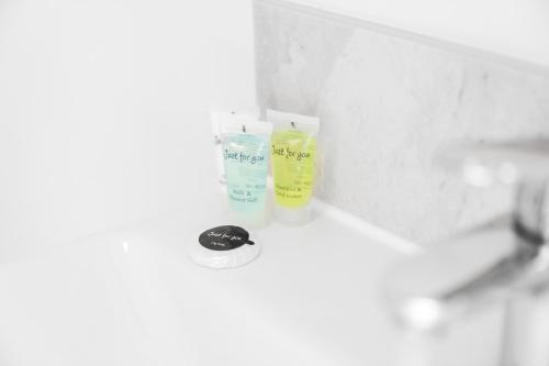 two bottles of detergent sitting on top of a bathroom sink at 2 Bedroom Apartment - Private Parking - Wifi - Netflix - Top Rated - 51C in Sleightholme
