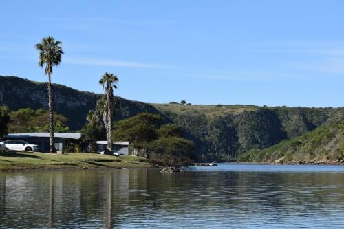 a house on the shore of a lake with palm trees at Areena Riverside Resort in Kwelera
