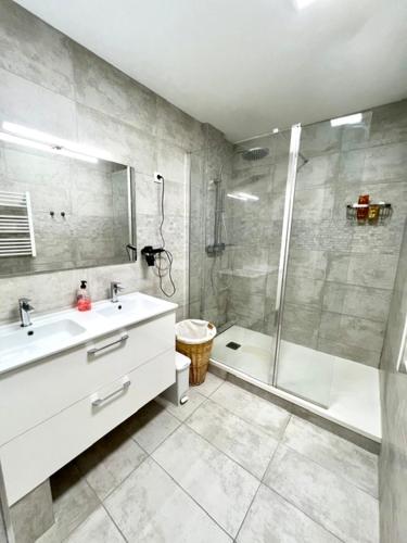 une salle de bain avec un lavabo blanc et une douche dans l'établissement Appartement en centre-ville, à Bussy-Saint-Georges