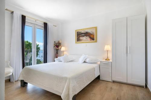 a white bedroom with a bed and a window at Villa with Sea View in Podgora