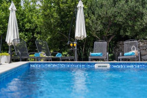 a swimming pool with chairs and umbrellas next to a pool at Villa with Sea View in Podgora