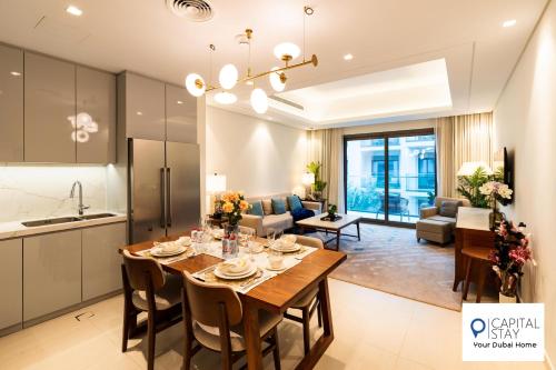 a kitchen and living room with a wooden table and chairs at Capital Stay- Private Two Bed Apartment - The Address Beach Resort Residences Fujairah in Fujairah