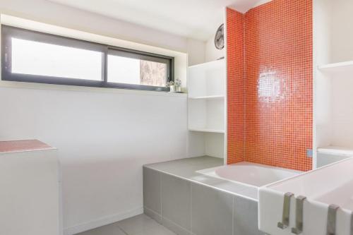 une salle de bain avec des murs blancs et un mur en carrelage rouge dans l'établissement Loft terrasse vue mer au coeur de Marseille, à Marseille