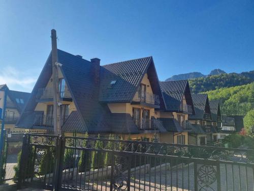 une maison avec un toit noir au-dessus d'une clôture dans l'établissement TatroManiac Zakopane Pokoje, à Zakopane