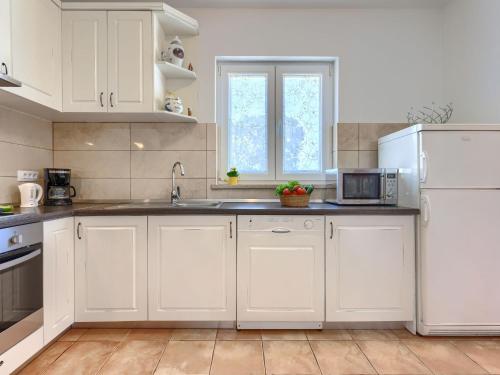 a white kitchen with a sink and a refrigerator at Villa Fuma by Interhome in Bale