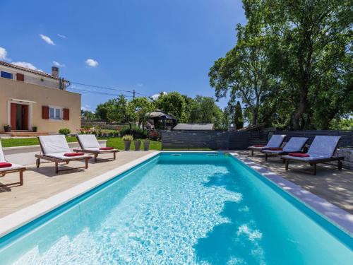 a swimming pool with lounge chairs next to a house at Villa Fuma by Interhome in Bale