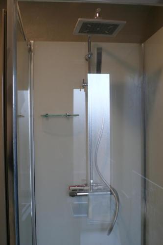 une douche dans une salle de bain avec une porte vitrée dans l'établissement Brise Marine, à Erquy