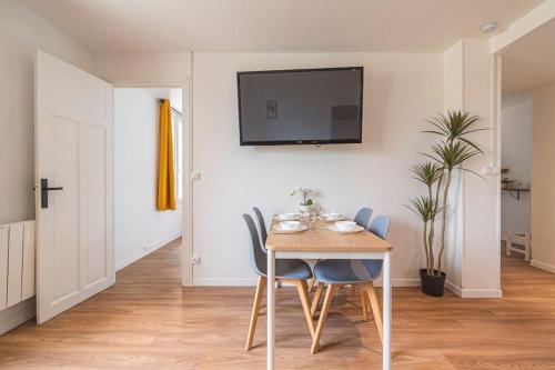 a dining room table with chairs and a tv on a wall at "Le chaleureux" Appartement pour 4 personnes in Isles-sur-Suippe