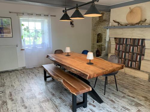 une salle à manger avec une table et des bancs en bois dans l'établissement Longère bord de mer avec grand jardin fleuri, à Géfosse-Fontenay