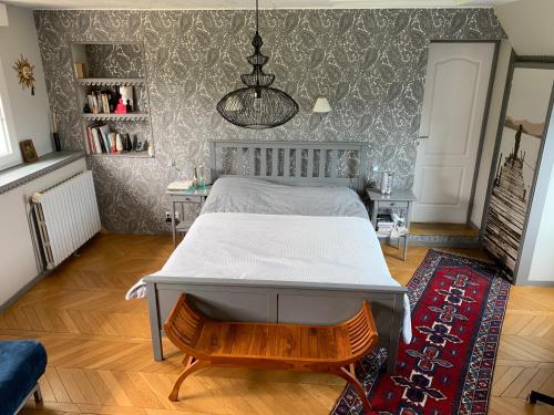 - une chambre avec un lit et un mur recouvert de papier peint dans l'établissement Longère bord de mer avec grand jardin fleuri, à Géfosse-Fontenay