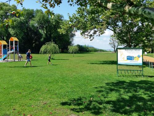 two people walking in a park with a sign in the grass at Chalet Rosso by Interhome in Balatonmáriafürdő