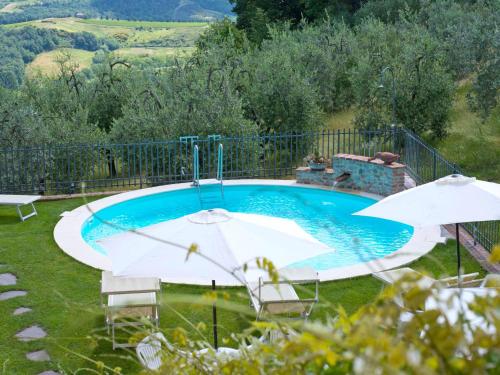 a swimming pool with two umbrellas in a yard at Apartment Lari-2 by Interhome in Luiano