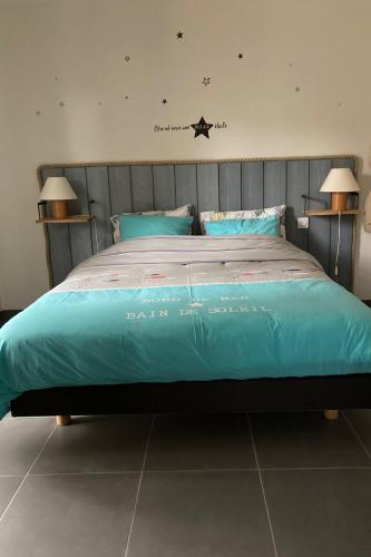 - un lit avec une couette bleue dans une chambre dans l'établissement Au grès des pins, à Erquy