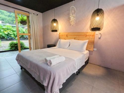 a bedroom with a bed with white sheets and a window at Hotel Casa de Hadas in Minca