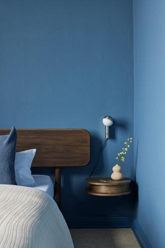 a blue bedroom with a bed and a table with a lamp at stilwerk Strandhotel Blankenese in Hamburg