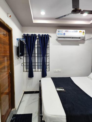 a small room with a bed with blue curtains at rest n' refresh in Visakhapatnam