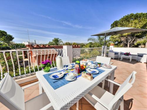 a white dining table with chairs and an umbrella on a balcony at Apartment MareLuna by Interhome in Fontane Bianche