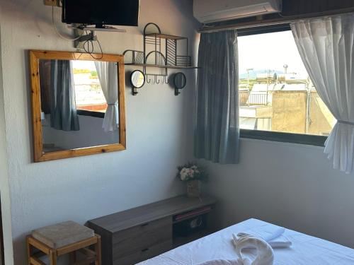 a bedroom with a mirror and a bed and a window at Dionisos Roses in Paralia Dionysiou