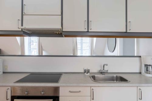 een keuken met witte kasten en een wastafel bij Unique Apartment w Exposed Beams Next to Tivoli in Kopenhagen