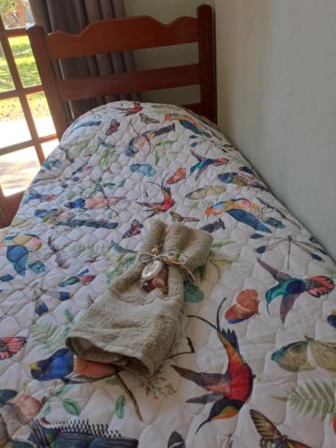 a bed with a quilt with a stuffed animal on it at Sitio CANTOS DA FLORESTA in Mairinque