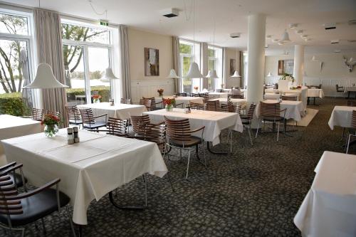 a restaurant with white tables and chairs and windows at Golf Hotel Viborg in Viborg