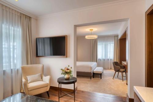 サンモリッツにあるGrand Hotel des Bains Kempinskiのベッドとテレビが備わるホテルルームです。