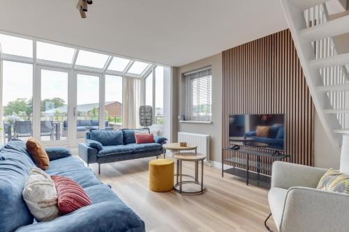 a living room with a blue couch and a tv at Meerzicht 57 - 3 bedroom appt with sunny terrace in Uitgeest